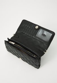 Portafoglio in pelle trapuntata nera con chiusura a scatto, diverse fessure per carte, una tasca trasparente per l'ID e un scomparto con zip.