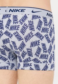 Bañadores de algodón en azul marino y azul claro con un patrón de hojas, con una cinturilla suave marcada con "NIKE" en letras azul marino.