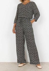Svart och vit mönstrad tvådelad outfit bestående av en lös blus med V-ringning och högmidjade vida byxor, tillverkad av lättviktig tyg.