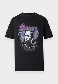 Sort bomulds T-shirt med et grafisk print af en figurs ansigt mod svulmende røg, med "Snoop" i lilla og "Dogg" i sort tekst ovenfor.