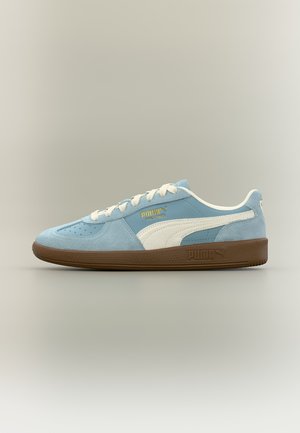 Χαμηλό μπλε δερμάτινο αθλητικό παπούτσι σουέντ με λευκή λωρίδα, λευκά κορδόνια και καφετιά σόλα, τοποθετημένο σε προφίλ σε ουδέτερο φόντο.