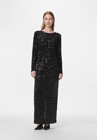 Crna večernja haljina ukrašena šljokicama, s dugim rukavima, okruglim izrezom i uskim krojem, dugu do poda s glatkom teksturom.