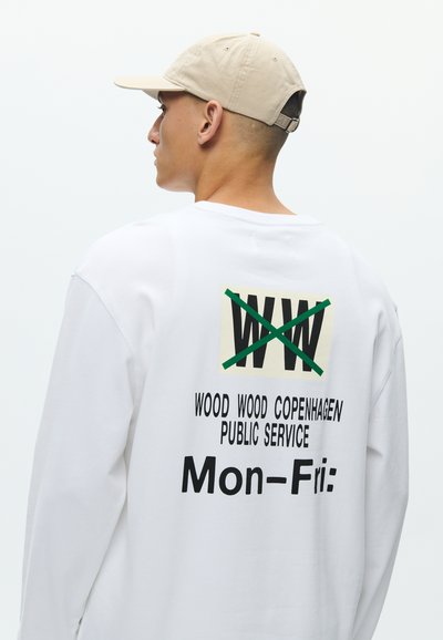 Λευκό πουκάμισο μακρυμάνικο με εκτυπωμένο σχέδιο στην πλάτη που απεικονίζει το "WW" με μία γραμμή, και κείμενο που γράφει "WOOD WOOD COPENHAGEN PUBLIC SERVICE Δευ-Παρ:" σε μαύρο χρώμα.