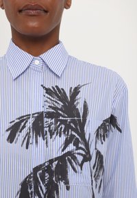 Gestreiftes blau-weißes Hemd mit einem schwarzen Palmblatt-Design. Normale Kragen, Knopfverschluss, glattes Material mit einer strukturierten Passform.