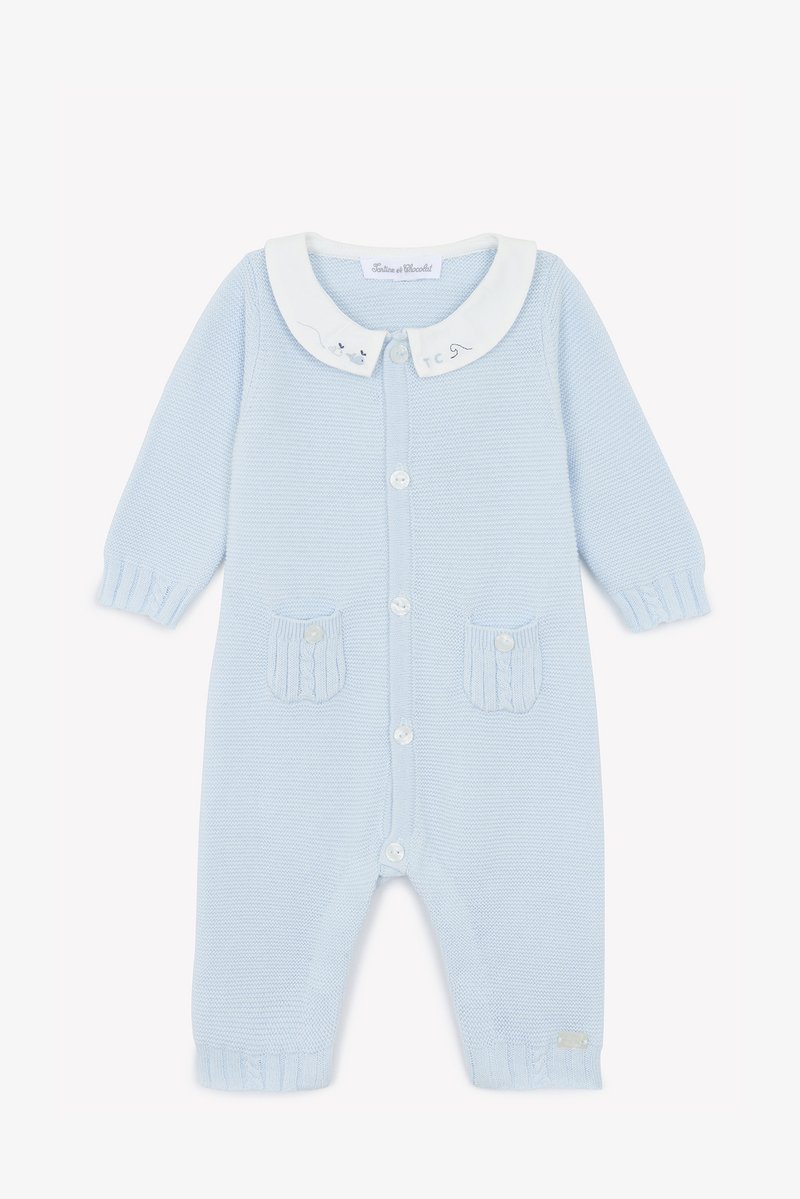 Svetlo modra pletena romper obleka z belim ovratnikom, sprednjim zapiranjem na gumbe, dvema teksturiranima žepoma in rebrastimi manšetami. Nežne vezenine na ovratniku.