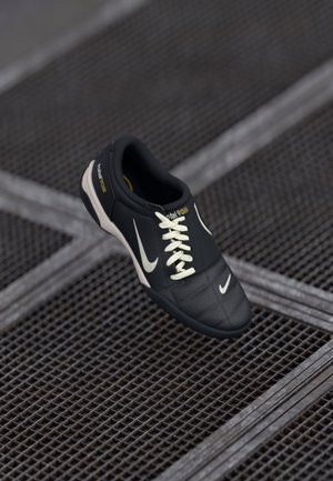 Sorte og hvide Nike sneakers med snørebånd, "total 90 III" branding, placeret på en metalgitteroverflade.
