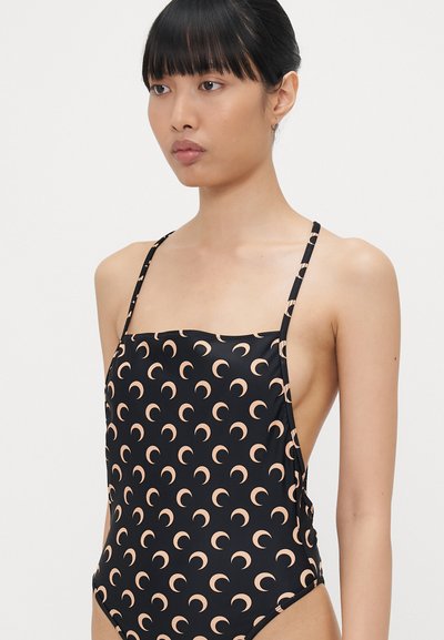 Costum de baie negru cu un model de lună în formă de semilună în nuanță piersică deschisă, având bretele subțiri și decolteu pătrat, realizat dintr-un material neted și elastic.
