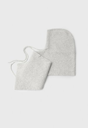 Bonnet de bébé tricoté gris clair et moufles assorties avec liens sur fond blanc.