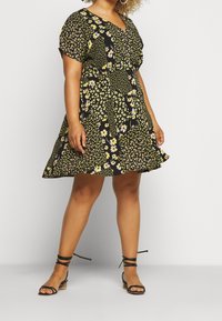 Schwarzes Blumenkleid mit kurzen Ärmeln, V-Ausschnitt, taillierter Taille und ausgestellt schwingendem Rock mit gelben und lila Blumenmustern.