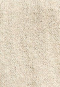 Tejido de punto en color beige claro con una textura suave y difusa. Presenta un patrón uniforme acanalado con ligeras variaciones en el hilo.