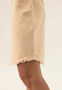 Różowa bawełniana spódnica z lekko rozkloszowanym dołem, z małą metką z logo w prawym dolnym rogu. Miękka tekstura i casualowy design.