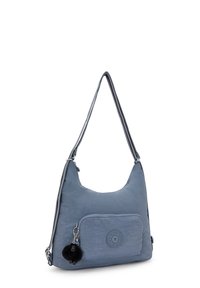 Sininen nylonselkäkassi, jossa on pyöristetty muoto, etupuolella vetoketjullinen tasku ja avaimenperäpompon yksityiskohta. Ominaisuuksiin kuuluu kuvioitu kangas ja logoväri.