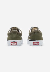 Olijfgroene suede en canvas sneakers met witte accenten, gevoerde kraag, zijlogo en een rode rubberen label op de hiel. Witte zool met zwarte rand.