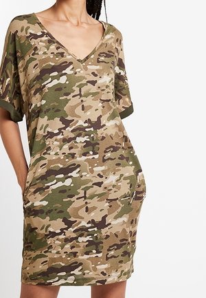 Robe imprimée camouflage, à manches courtes, avec un décolleté en V, dans des tons de vert et de beige, avec un détail de poche sur le côté. Texture de tissu douce.