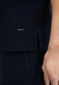 Marineblauw textiel top met een gestikte zijspleet, voorzien van een metalen label met de gravure "JOOP!" aan de ondernaad.