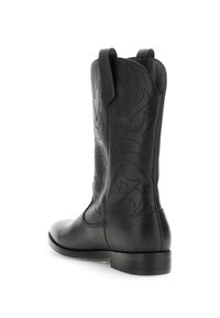 Botas de vaquero de cuero negro con un caño alto, costuras tonales intrincadas, punta redondeada y un ligero tacón. Presentan una lengüeta en la parte posterior.
