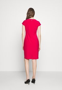 Růžové přiléhavé šaty s krátkými rukávy, zadním zipem a malým rozparkem na lemu. Hladká látka s čistým a jednoduchým designem.