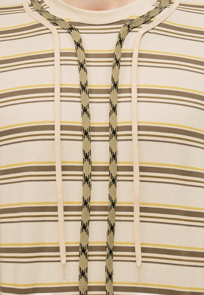 Sweat à capuche beige avec de fines rayures horizontales marron et jaunes, doté de deux cordons beiges et de deux cordons plus épais à motifs beige et noir.