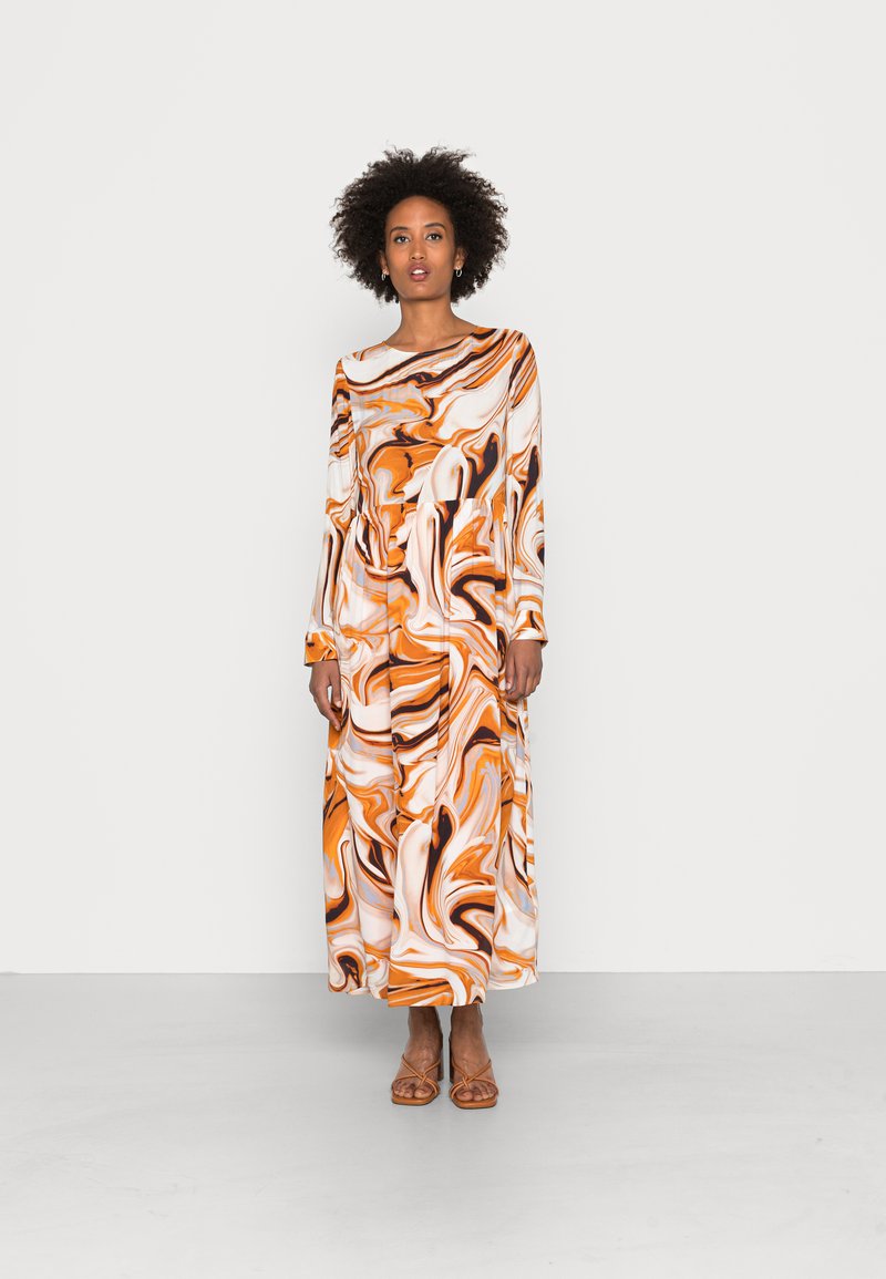 Kratka obleka z dolgimi rokavi z oranžno, belo in črno marmoriranim vzorcem. Narejena iz gladkega materiala, ima sproščen kroj in okroglo ovratnico.