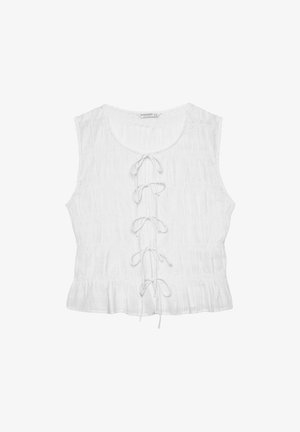 Hvid ærmeløs top lavet af tekstureret stof. Har en rundet halsudskæring og en frontlacing detalje med løse snore. Flæset kant.