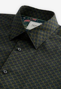 Grün und marineblaues Hemd mit einem sich wiederholenden abstrakten Muster. Verfügt über einen Button-Down-Kragen und kontrastierendes florales Futter. Zwei graue Knöpfe sichtbar.