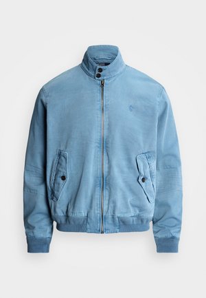 Lichtblauw jack met ritssluiting, hoge kraag, klepzakken met knopen, geribde boorden en zoom, en een subtiel geborduurd logo op de borst.