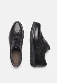 Scarpe nere in pelle con una finitura testurizzata, caratterizzate da dettagli decorativi in brogue, punta rotonda e una suola spessa in gomma per una maggiore aderenza.