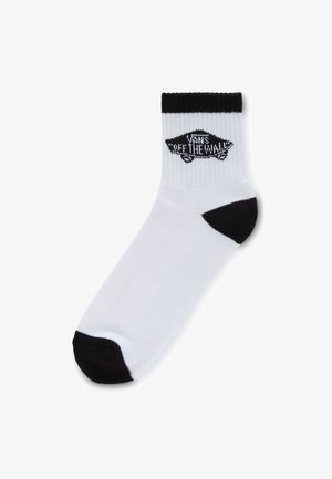 Białe skarpetki sięgające kostek z czarnym piętą i palcami, prążkowaną fakturą oraz czarnym logo "Vans Off the Wall" po zewnętrznej stronie.