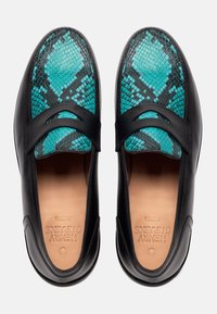 Scarpe in pelle nera con tomaia in tessuto a motivo serpente turchese e nero. Presentano una finitura liscia, punta rotonda e bande elastiche per facilitare l'indossamento.