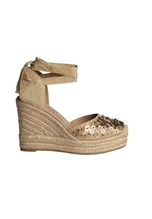 Alpargata de cuña beige con suela de yute trenzado, lazos para atar en el tobillo y adornos florales de lentejuelas en la puntera cerrada.