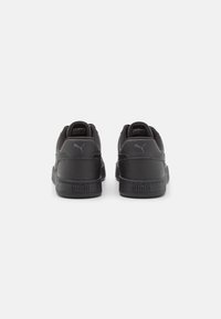 Schwarze Sportschuhe mit einem glatten Leder-Obermaterial, gepolstertem Kragen und Logodetail. Strukturierte Sohle und minimalistisches Design.