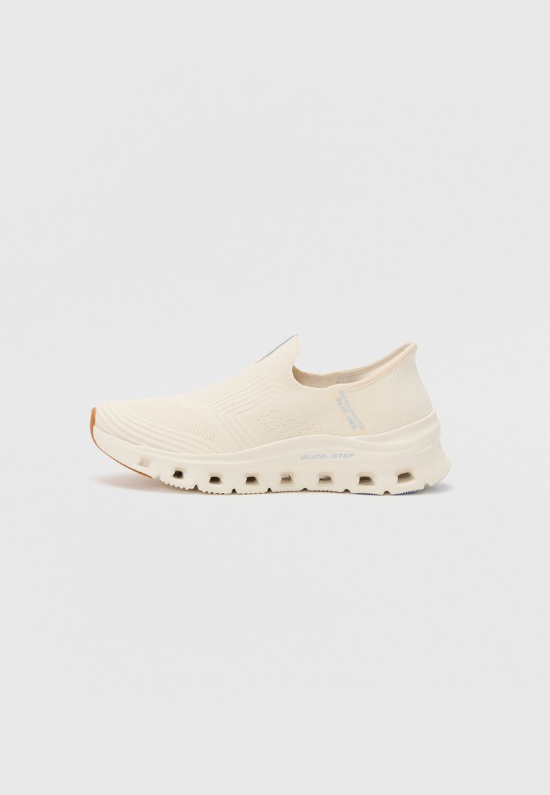 Béžová slip-on teniska s texturovaným svrškem, polstrovanou podrážkou a zvýrazněným designem podrážky s kruhovými výřezy. Minimalistické logo viditelné.