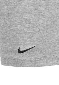 Gray cotton shorts featuring a black Nike swoosh logo. Smooth texture with an elastic waistband and hem stitching detail.