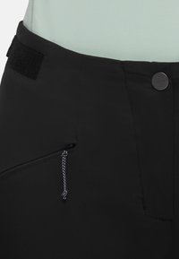 Zwarte stoffen broek met een gladde textuur, een voorzak met rits en een trekkoord, en een klittenbandsluitingen voor aanpassing van de taille.