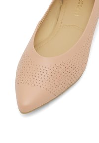 Baleriny w odcieniu miękkiego różu z ostro zakończonym noskiem, z geometrycznymi wycięciami na cholewce, o gładkim, matowym wykończeniu i podszyciu.