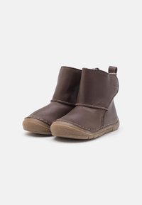 Bottines en cuir marron avec une finition lisse, bout rond, détails cousus et semelle en caoutchouc. Comprend une languette pour un enfilage facile.