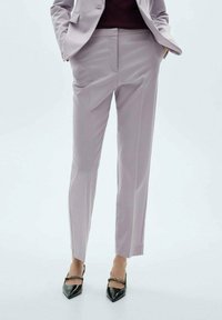 Pantaloni liliachii, ajustați, cu o textură fină, design slim fit și linii curate. Asortați cu pantofi cu toc negru, cu vârf ascuțit, având un accent din lanț.