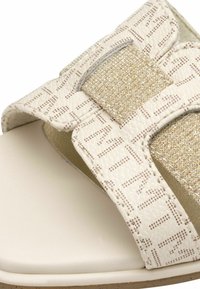 Sandali di un beige chiaro con una fascia testurizzata che presenta accenti di glitter dorato, chiusura regolabile e una soletta liscia di colore crema.