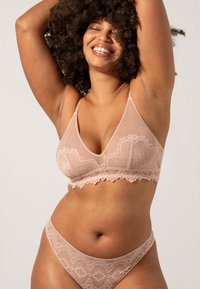 Rintareunalla varustettu, läpikuultava vaaleanpunainen bralette ja siihen sopivat thong-alusvaatteet. Ominaisuuksina on kolmiomainen muoto, jossa on herkkiä kukkakuvioita ja säädettävät olkaimet.