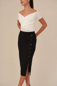 Bijela off-shoulder majica s drapiranim materijalom uparena s crnom olovkastom suknjom koja ima bočni prorez i šest smeškastih dugmadi.