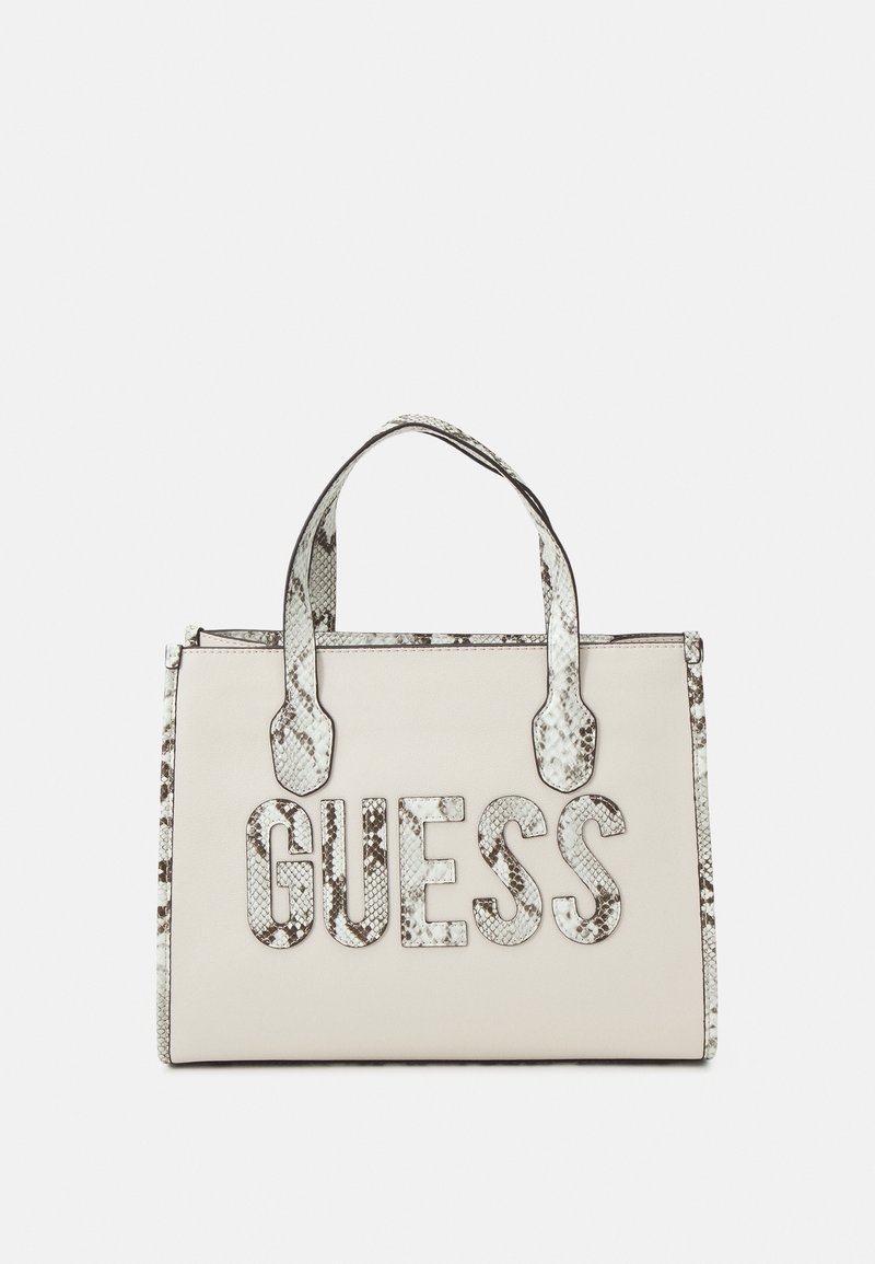 Sac fourre-tout crème avec garniture et poignées en peau de serpent, comportant un grand logo "GUESS" texturé à l'avant.
