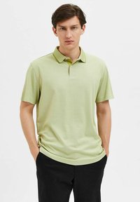 Polo de color verde claro fabricado en un tejido suave, con cuello, mangas cortas y un sutil ribete de contraste a lo largo del cuello.