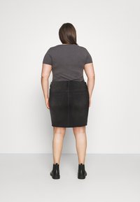 Schwarzer Jeansrock mit Gesäßtaschen, gesäumtem Saum und glatter Textur, kombiniert mit einem taillierten grauen T-Shirt und Ankle Boots.
