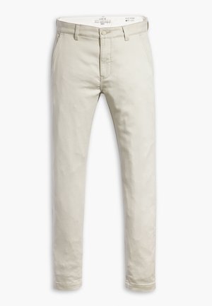Chinos de un color beige claro con corte ajustado, confeccionados en suave tela de algodón. Cuentan con cremallera, trabillas para cinturón y bolsillos frontales.