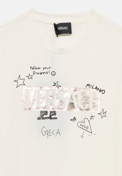 Λευκό βαμβακερό t-shirt με μεταλλικό ασημί λογότυπο "VERSACE", σκίτσα σε στιλ ζωγραφιάς και κείμενα όπως "Ακολούθησε τα όνειρά σου!" και "Μιλάνο".