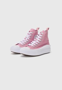 Baskets montantes en toile rose avec semelles en caoutchouc blanc, lacets plats, œillets en métal et patch logo sur le côté. Tige texturée et languette de tirage.