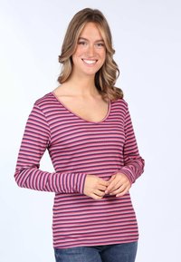 Langärmliges, V-Ausschnitt-Shirt mit horizontalen rosa und lila Streifen. Weiche, gerippte Textur mit eng anliegenden Ärmeln. Getragen mit blauen Jeans.