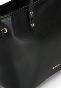 Zwarte totebag van gestructureerd synthetisch leer. Voorzien van goudkleurige hardware en logo, met dubbele handvaten en een ruime binnenkant.