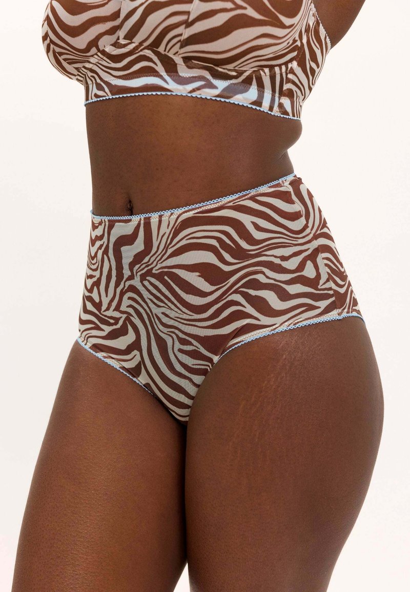 Nahaufnahme einer Person, die braune und weiße, zebragestreifte, hoch taillierte Unterwäsche und einen passenden BH mit hellblauer Einfassung trägt.