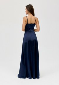Dlouhé námořnicky modré saténové šaty s těsně přiléhajícím živůtkem a tenkými ramínky. Hladká textura, dlouhé až na zem, s jemným detailem zapínání vzadu.